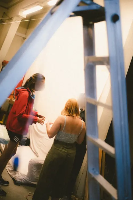 Menschen im Raum hinter einer blauen Leiter
